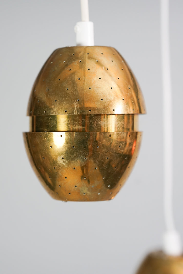 Two similar brass lamps with a thinner part in the middle. The lamps have tiny holes decorating them.