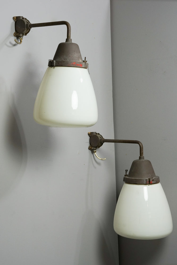 Two similar lamps with iron frames and white cloudy glass domes. The domes widen at the bottom.
