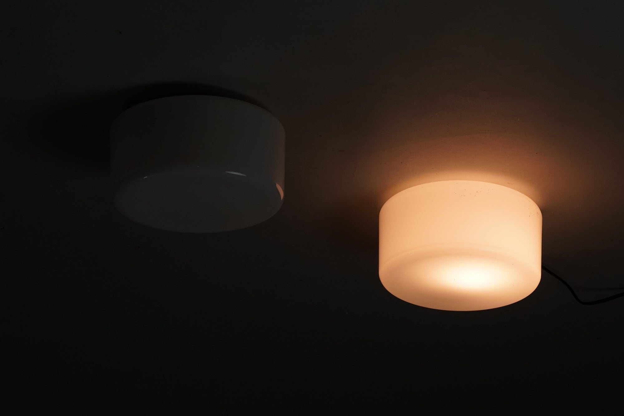 Cylinder shaped plafond made of white cloudy glass. The frame of the lamp is metal.