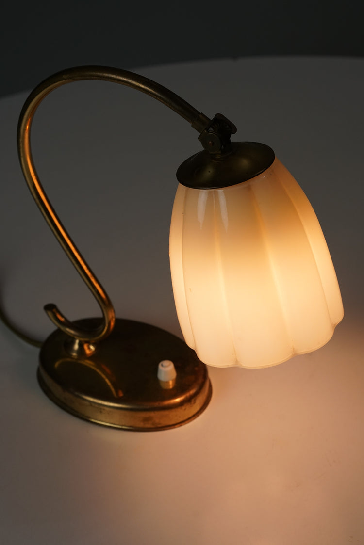 Curved brass leg and base, with a white switch. White opal glass dome in a shape of a flower.