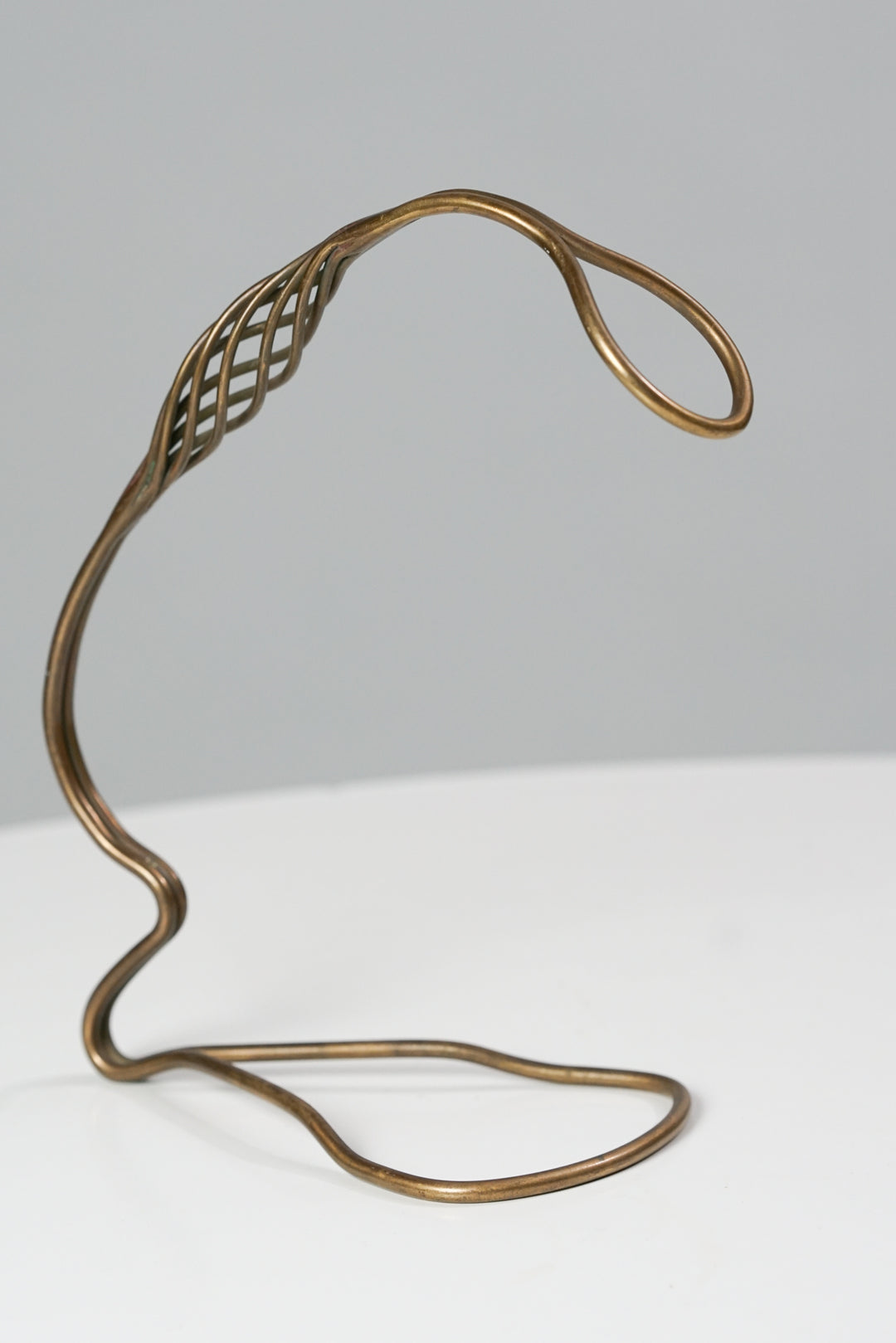 Brass bottle holder that stands up. The shape of the holder is curved.