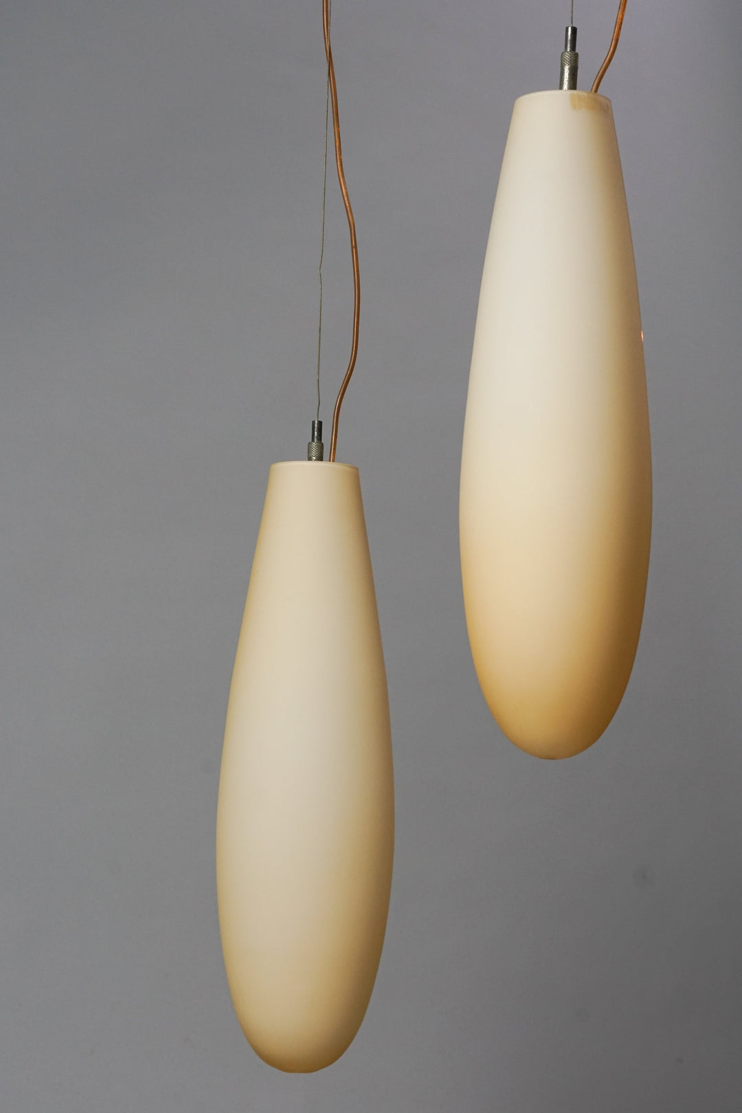 Two oval shaped lamps made of opal glass, that are yellowish white in color.
