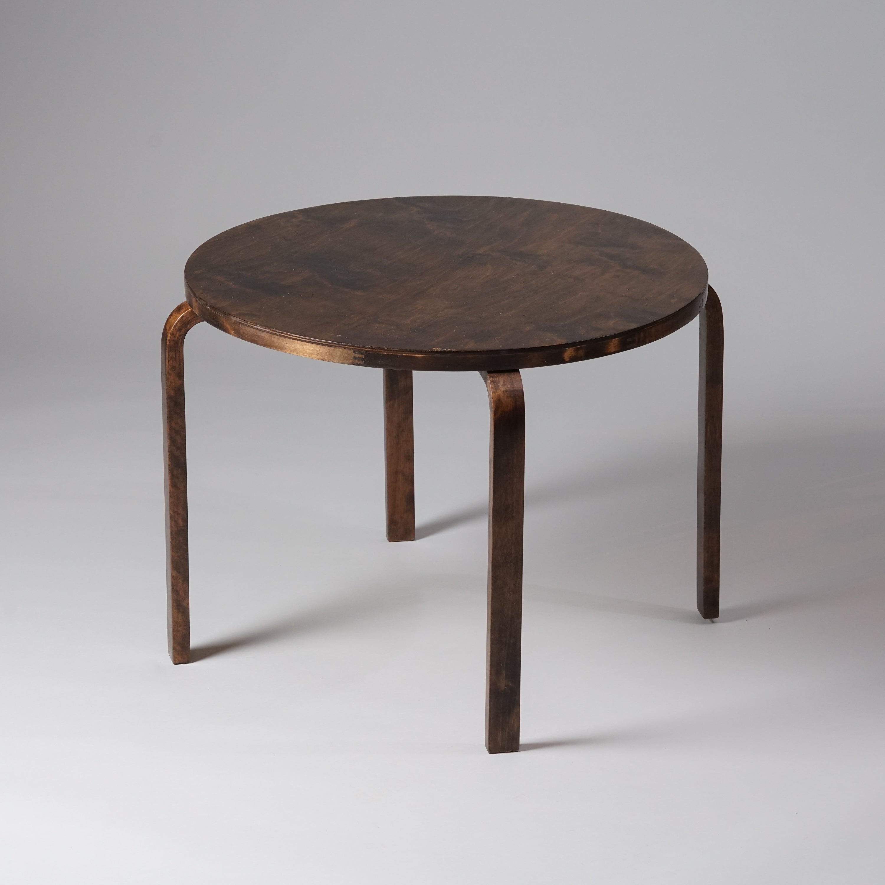 Ympyränmuotoinen puinen pöytä, joka on sävyltään tummanruskea.