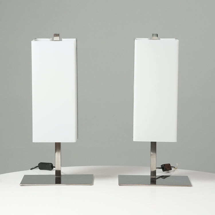 Two identical lamps. The shape of the white acrylic shade is of a rectangle and the base of the lamp is made of metal.