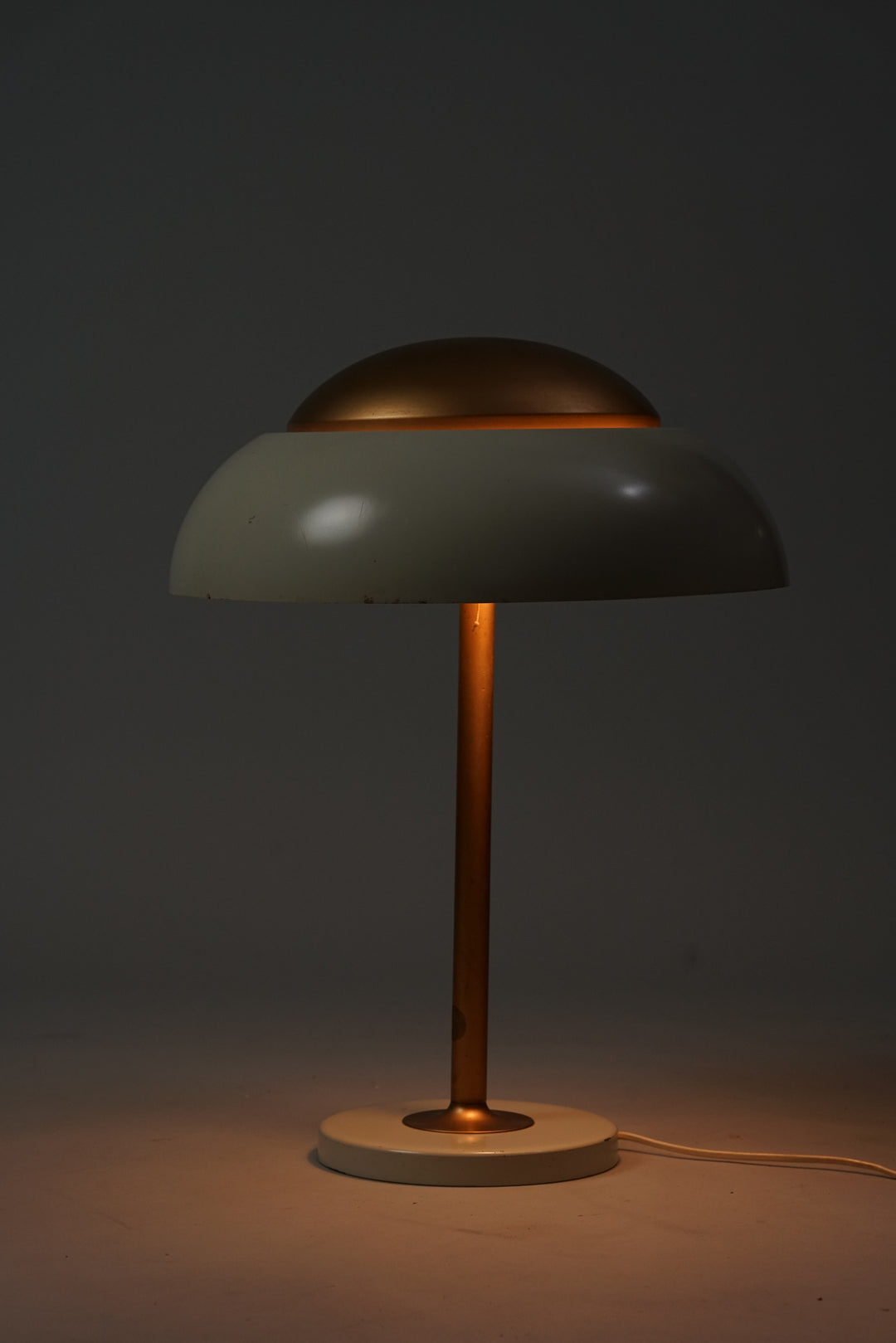 Painted metal lamp with the leg and top part of shade being bronze color and the rest white.