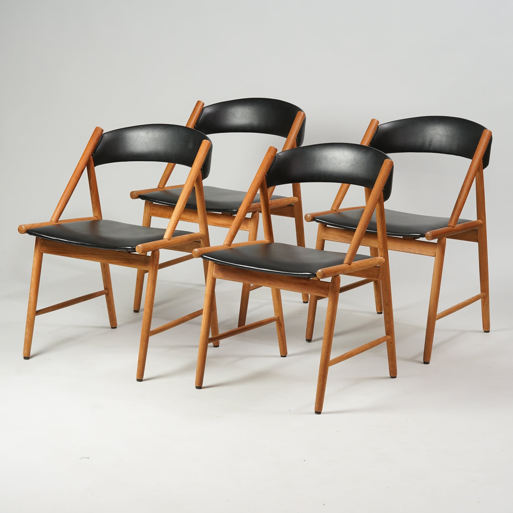 Neljä samanlaista tuolia. Tuolit on tehty tammesta, istuimet ja selkänojat keinonahkaa.