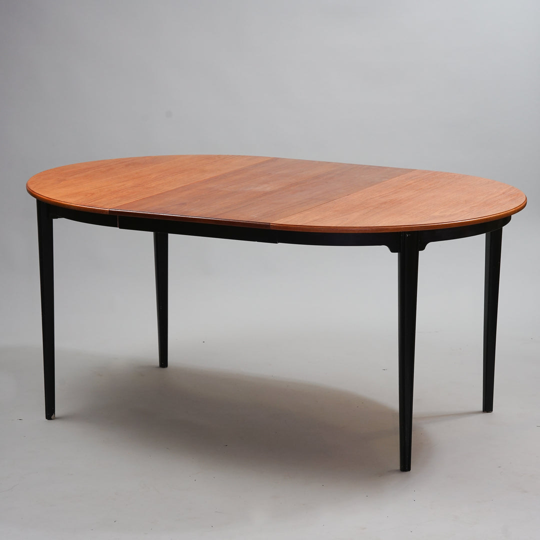 Round extendable table where the top and extra part are teak. The legs are wood, painted black.
