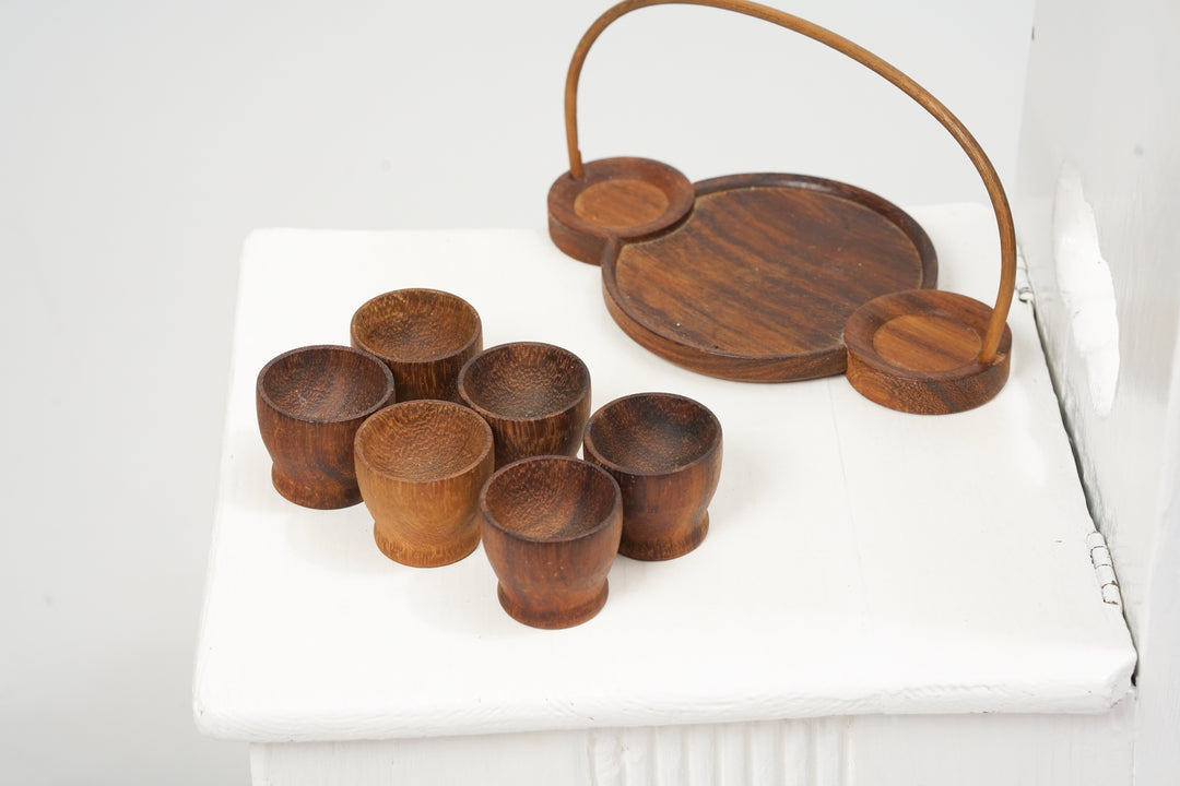 Six teak egg cups with a wooden holder.