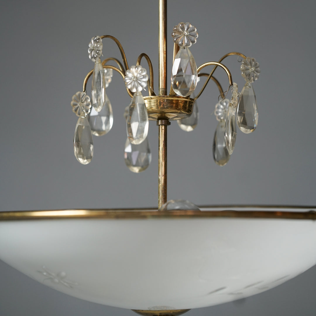 Pendant that has a brass frame. Crystal flowers and droplets on the middle. The lampshade is made of frosted glass with flower details.