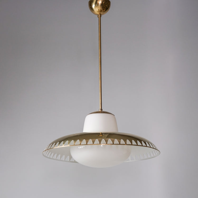 Pendant with white round glass dome in the middle. The glass bubble holds a brass shade  with a row of triangular holes along the edge.