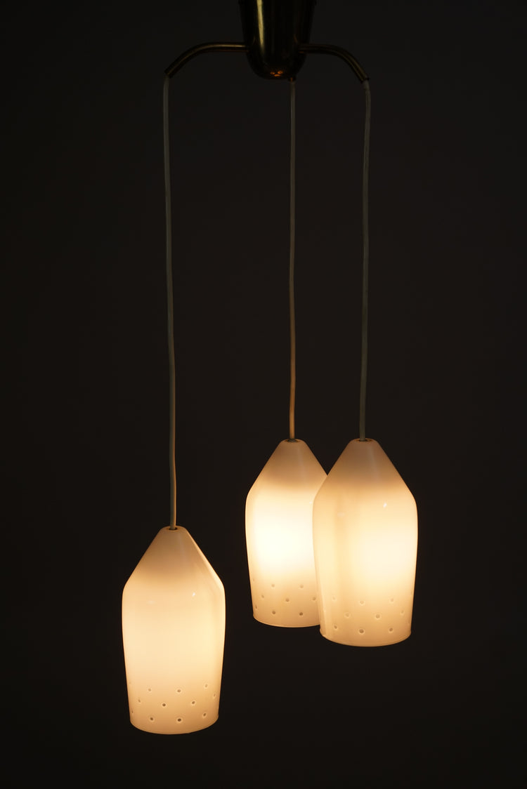 The frame of the lamp is brass and the domes white opal glass. The domes have tiny holes in them for light to get through.