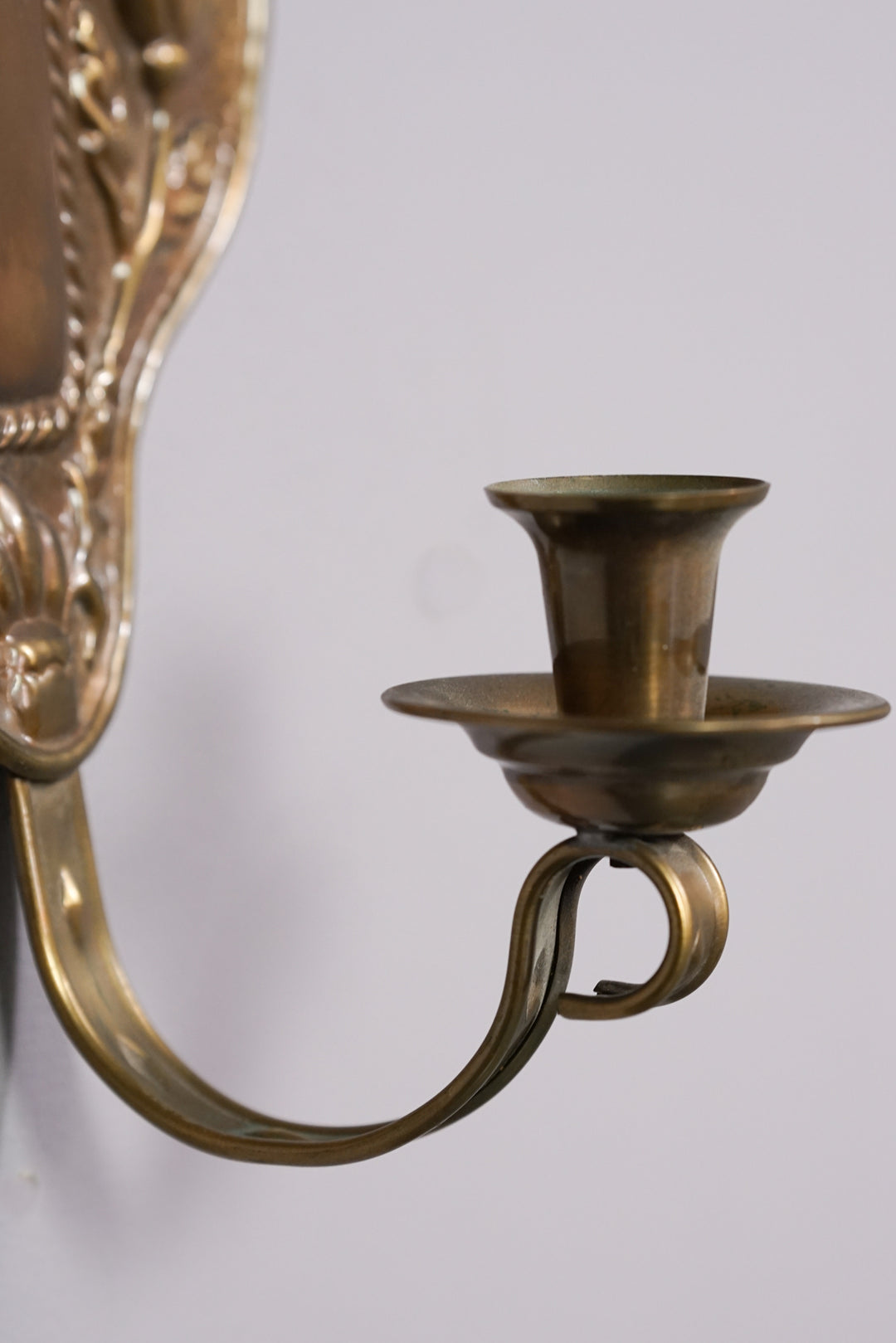 Brass wall sconce with flower inspired decoration and one holder.