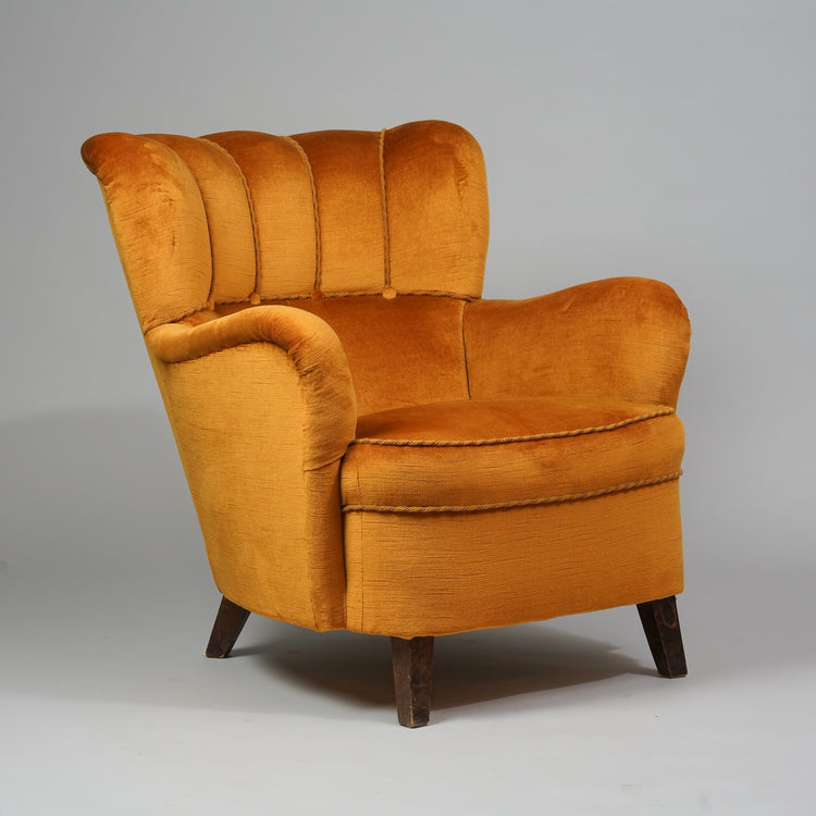 Orange armchair with four dark wooden legs. Round shapes. Four buttons on the backrest.