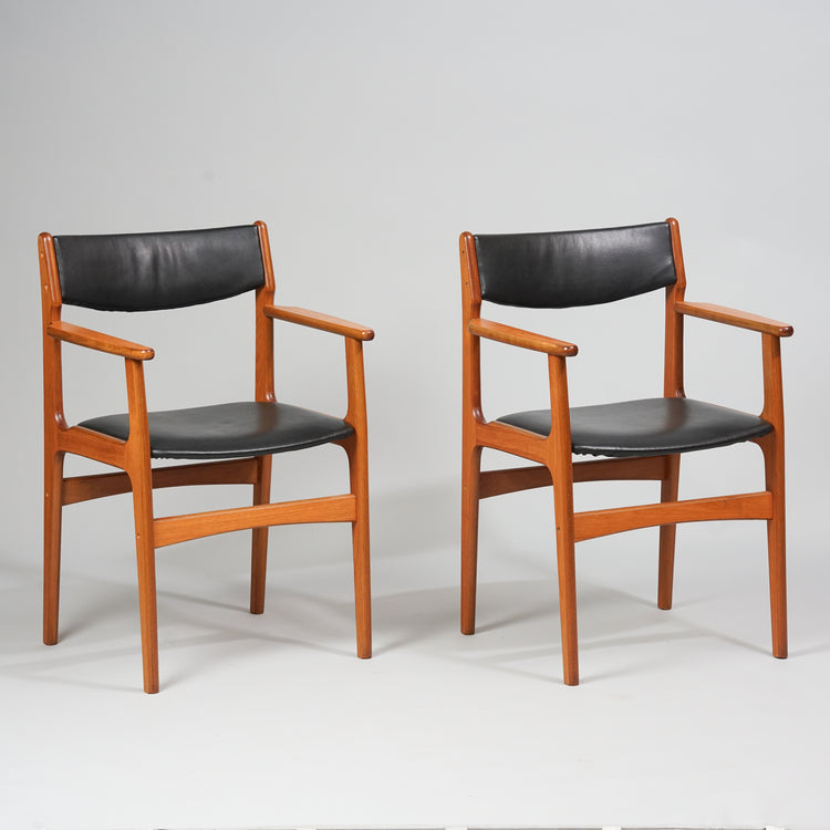 Brown teak chair with straight armrests and four legs. Supports between the legs. Black leather upholstery. 