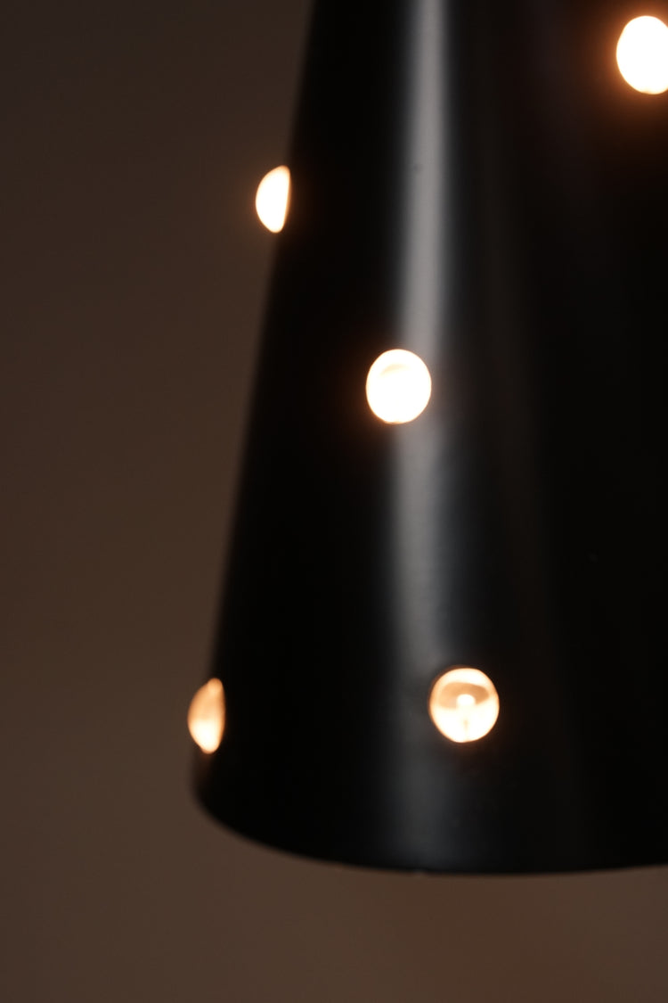 Cone-shaped black ceiling light with brass ceiling fixture. The cone has glass balls that reflect the light. The inside of the cone is white.