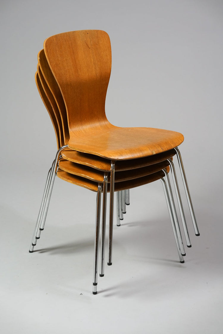 Four identical chairs made of wood. The chairs have metal legs and a backrest that widens.