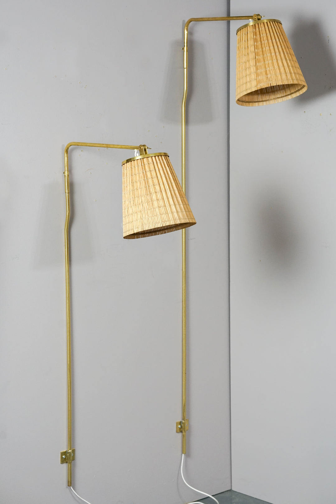 Two wall lights. Thin brass frame. Wooden shades. Shades and lamp body can be rotated in different directions. The lamps are identical but of different lengths. 