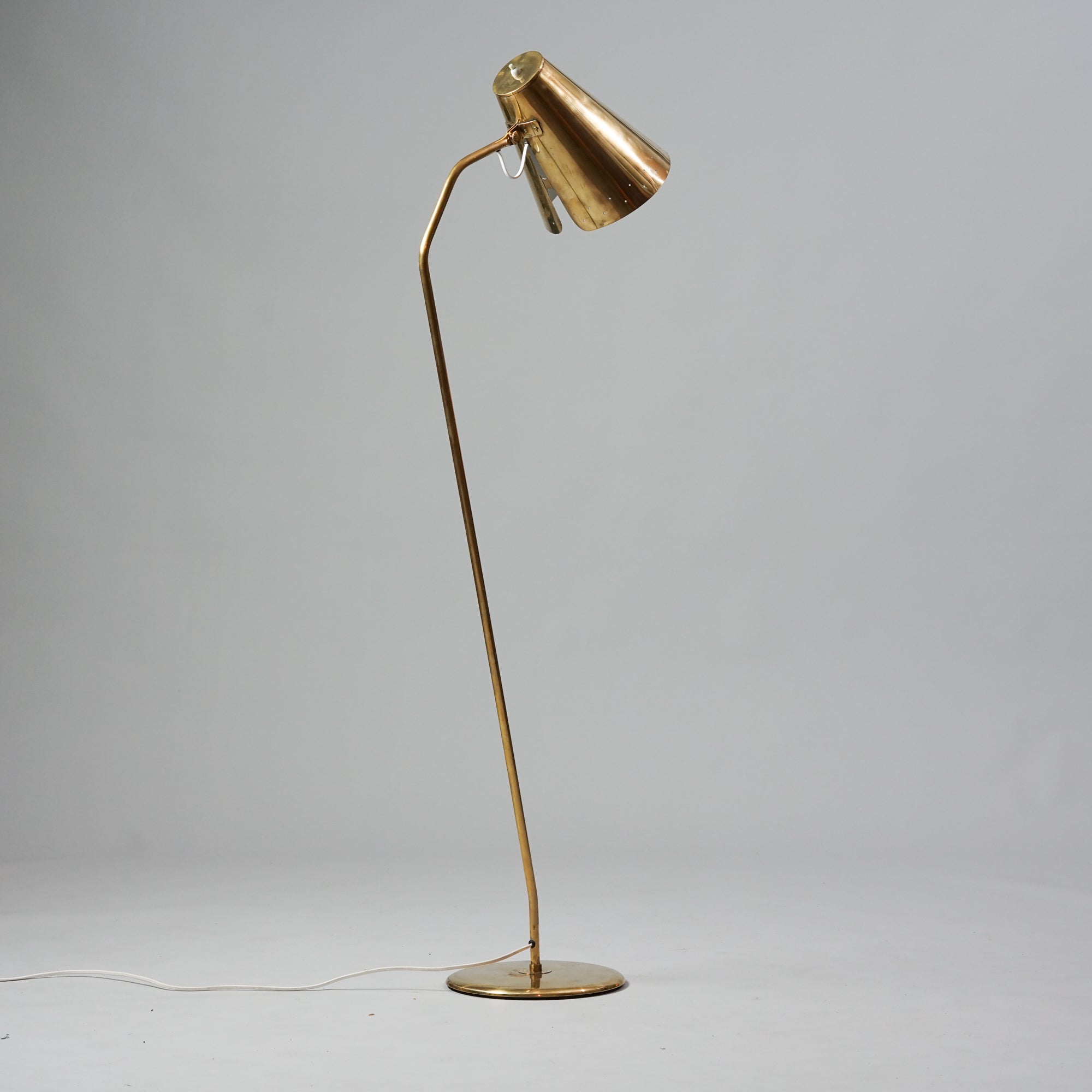 Brass lamp with a thin leg. Small holes decorate the rim of the shade.