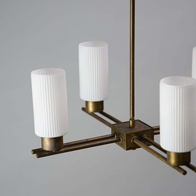 A lamp with four white cloudy glass domes. The base of the lamp is made of brass.