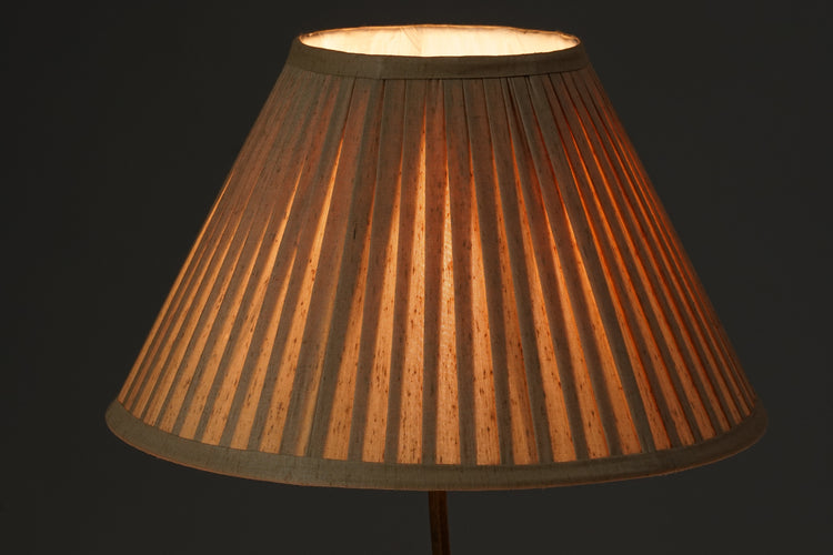 Brass lamp with beige pleated shade.