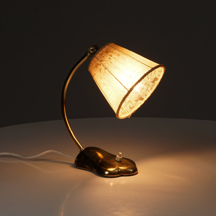 Brass lamp with the light switch right in middle of the base. Plastic lace shade in a beige color.