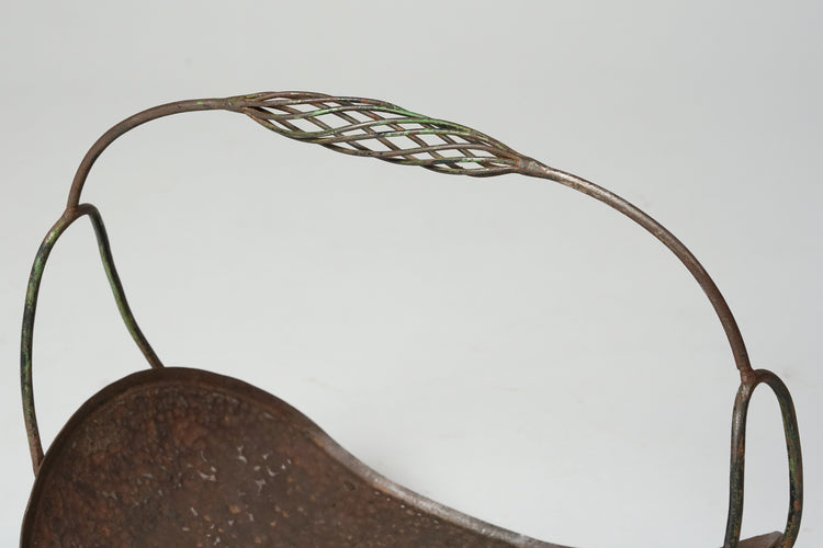 Wrought iron log basket, with a handle that is decorated at the middle.