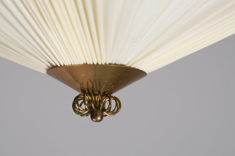 White square plafond, the shade made of plastic and has a pleated design. The sides and middle of the lamp has a brass detailing.