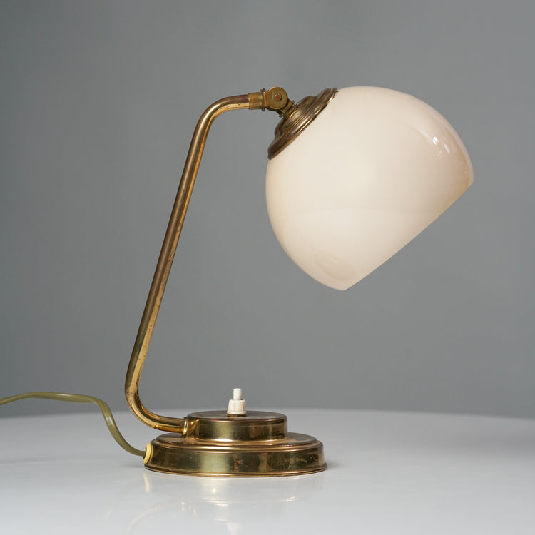 Brass base lamp with a switch in middle of the base. The dome is white opal glass.