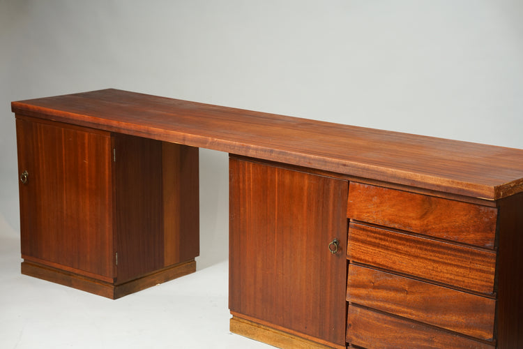 long wooden desk with three cabinets below. One of the cabinets has four drawers.