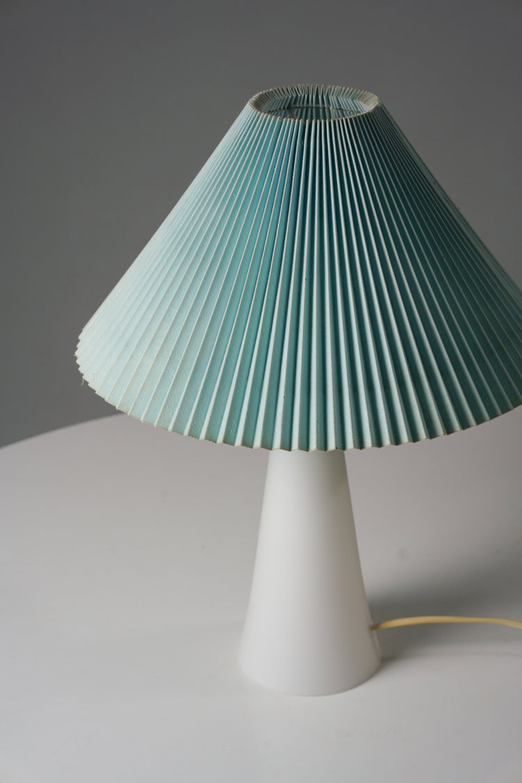 Table lamp with a light blue pleated shade and a white base.