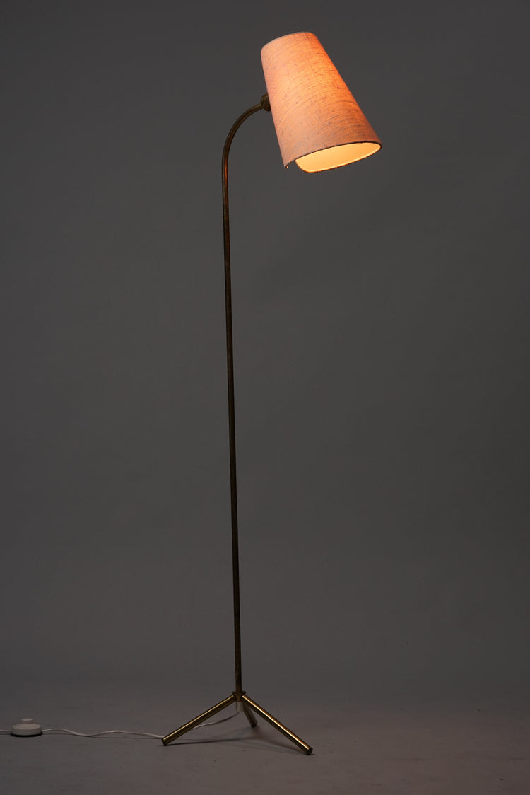 The shade of the lamp is light flax and the leg is made of brass.