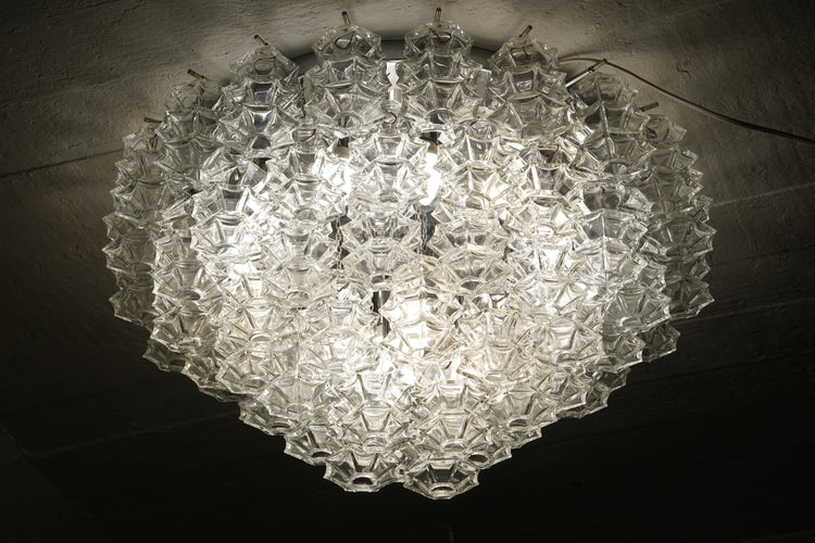 A plafond made of clear glass pieces shaped like diamonds. The base of the lamp is made of chromed metal. 