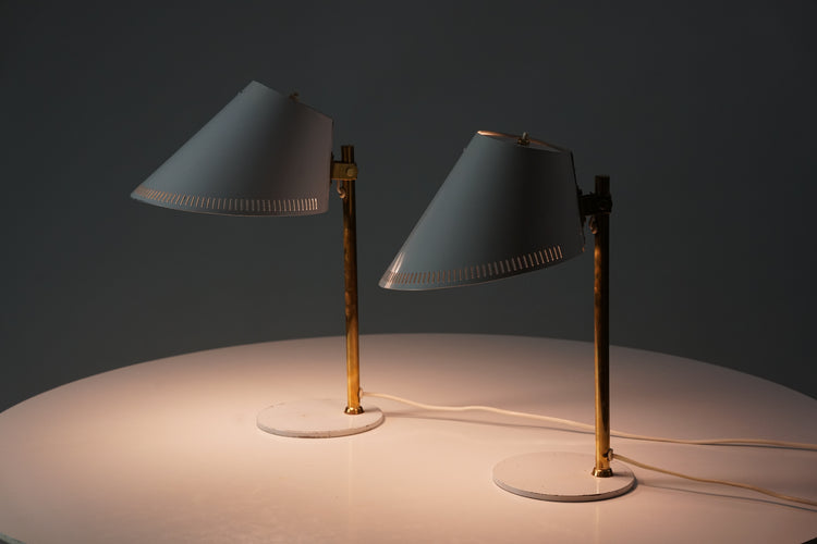Two identical lamps with brass legs. The shade and base of the lamp is white painted metal.