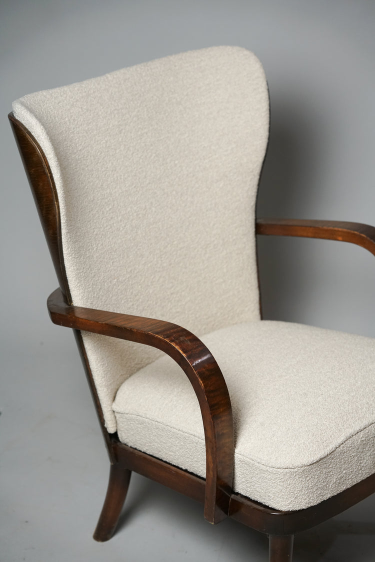 Wingback chair made from dark wood. The seat is upholstered in white fabric.