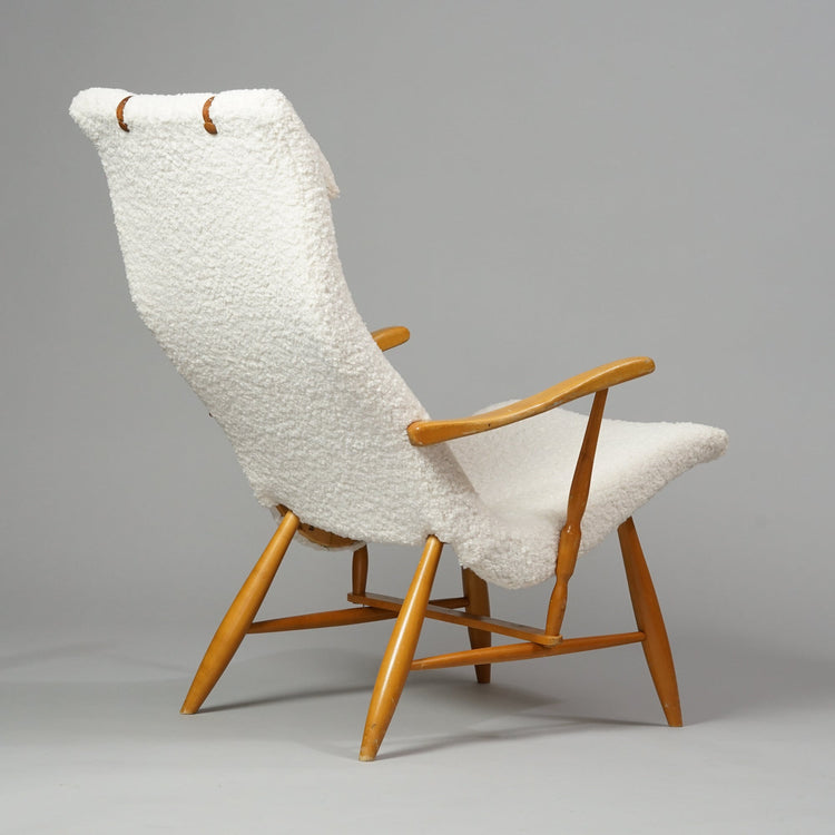 Birch frame armchair upholstered in white fabric. There are leather details on the backrest and a fabric pillow.