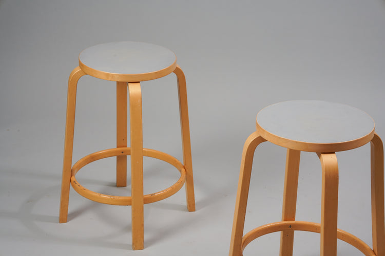 A stool made of birch with four legs and a round seat.  The seat has a grey linoleum top.