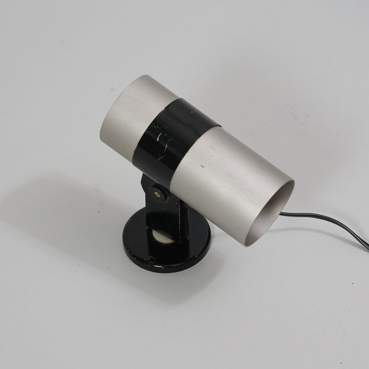 A wall lamp made of metal with the base and middle being black. Otherwise the lamp is grey in color.