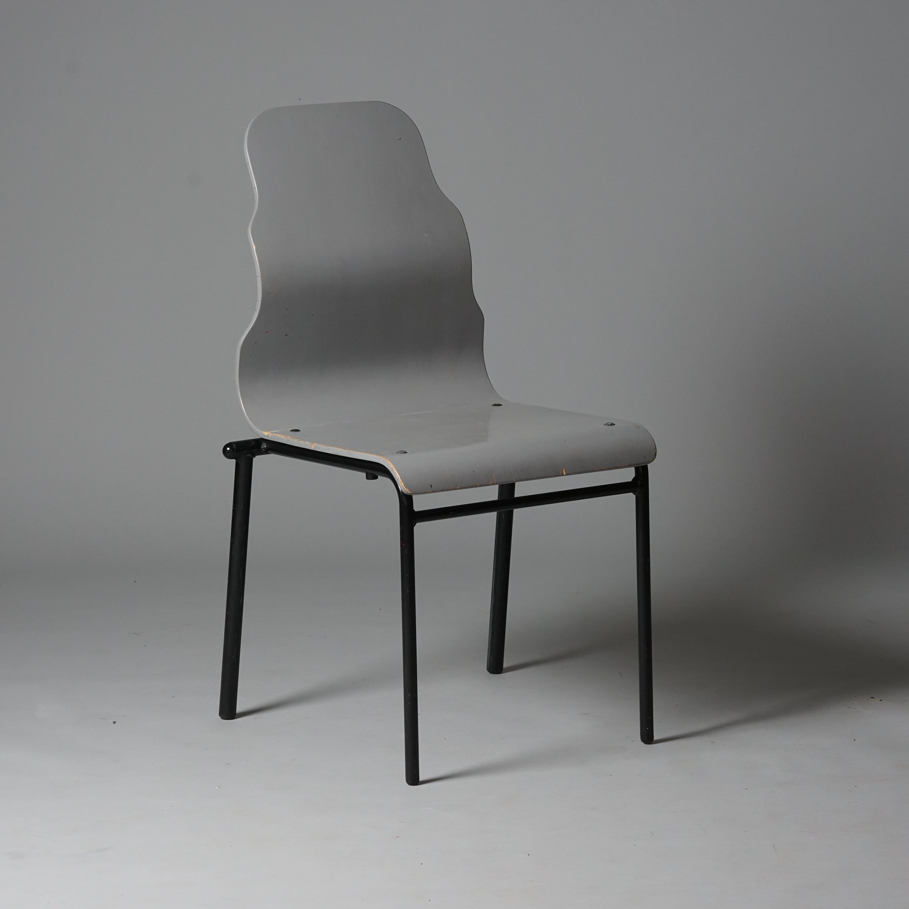 Tuoli on tehty puusta ja jalat metallista. Istuimen selkänojan muoto on aaltomainen. Väriltään istuin on harmaa ja tuolin jalat mustat. 