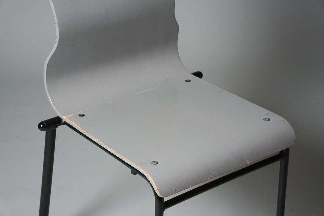 The seat is made out of wood with metal legs. The chair's backrest is an unique wave shape and is grey in color. The legs are black.