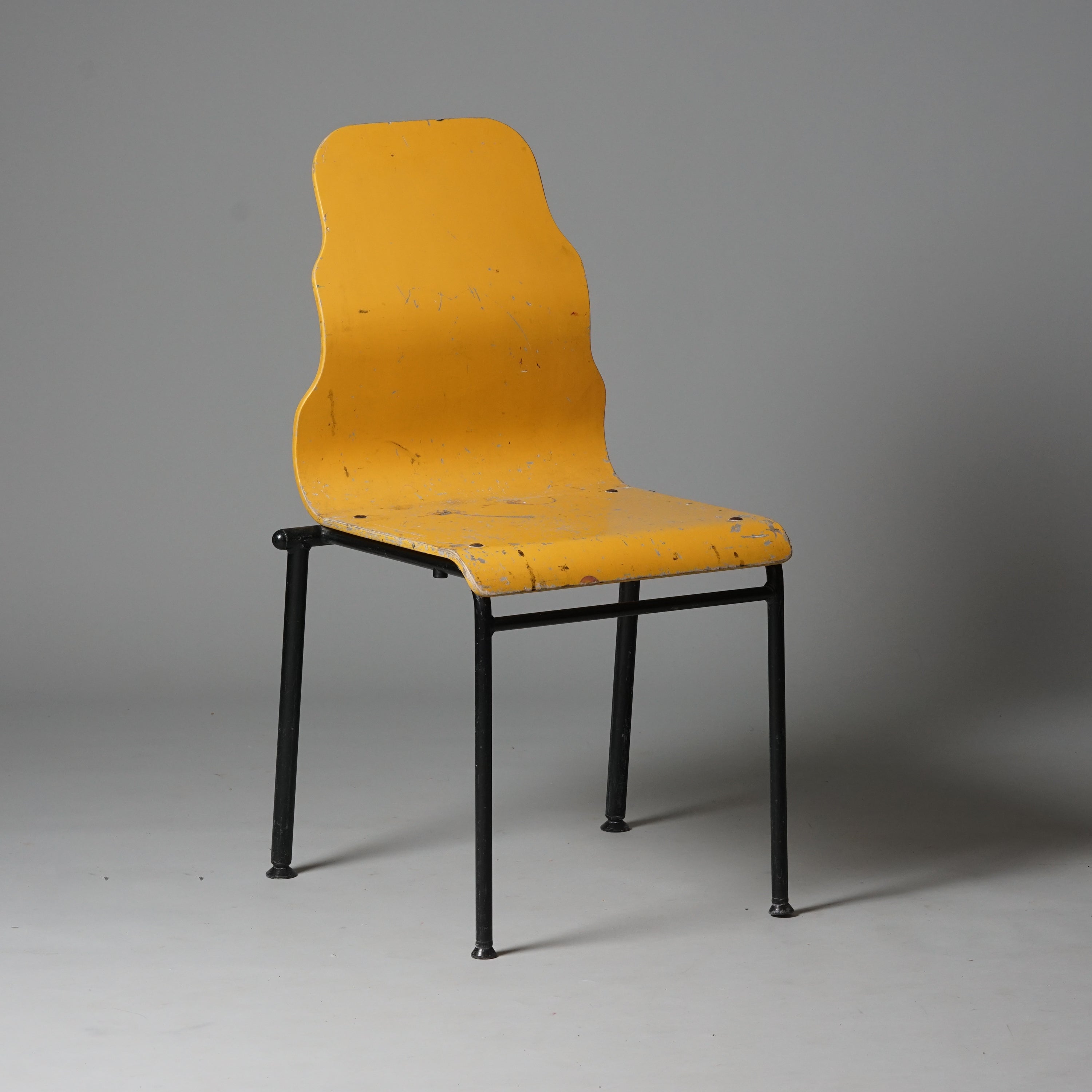 Tuoli on tehty puusta ja jalat metallista. Istuimen selkänojan muoto on aaltomainen. Väriltään istuin on keltainen ja tuolin jalat mustat.