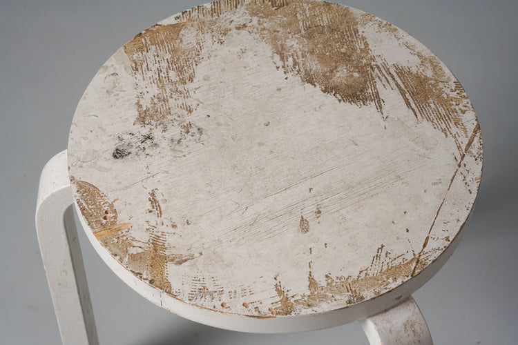 Three legged stool made of birch with a round seat. The stool is painted white.