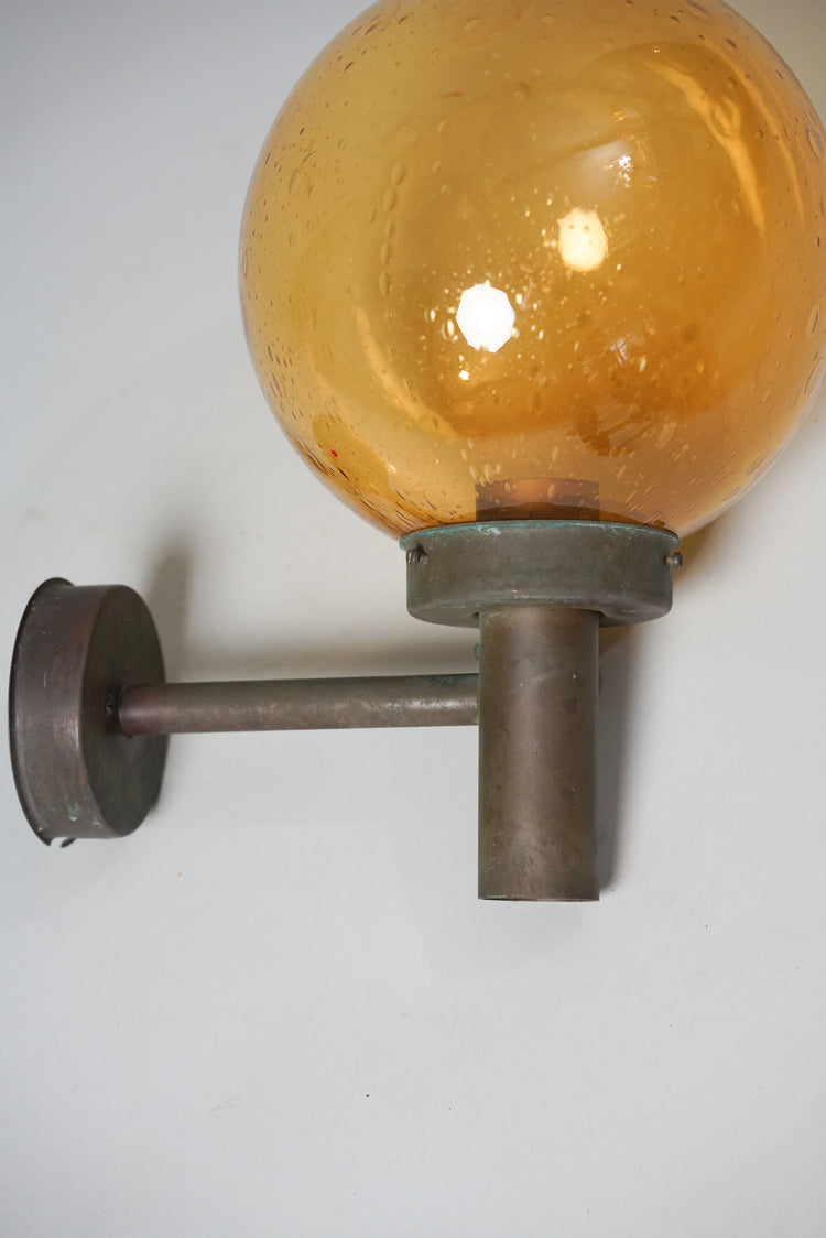 Outdoor lamp with a amber colored dome and base made of copper.