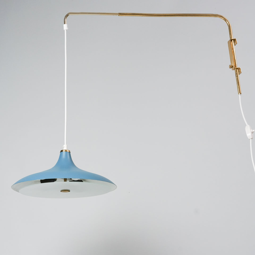 The lamp's metal shade is blue, with a glass part below it. The base of the lamp is made of brass. 