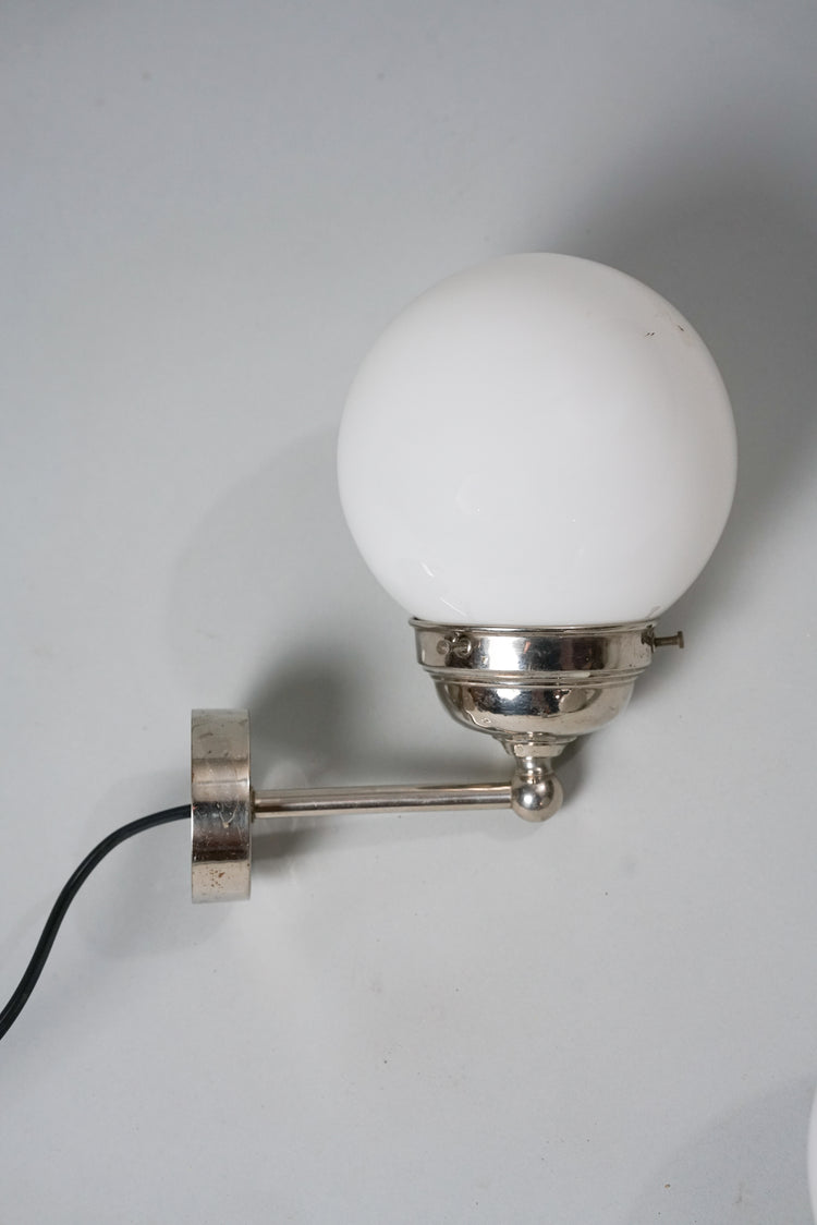 Wall lamp with milky white dome and chromed metal frame.