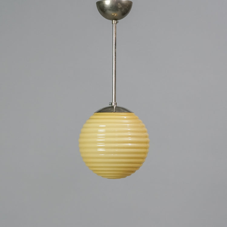 Yellow round dome covers the light. The dome has wavy texture and is made of opal glass. The base is made of nickel-plated brass.