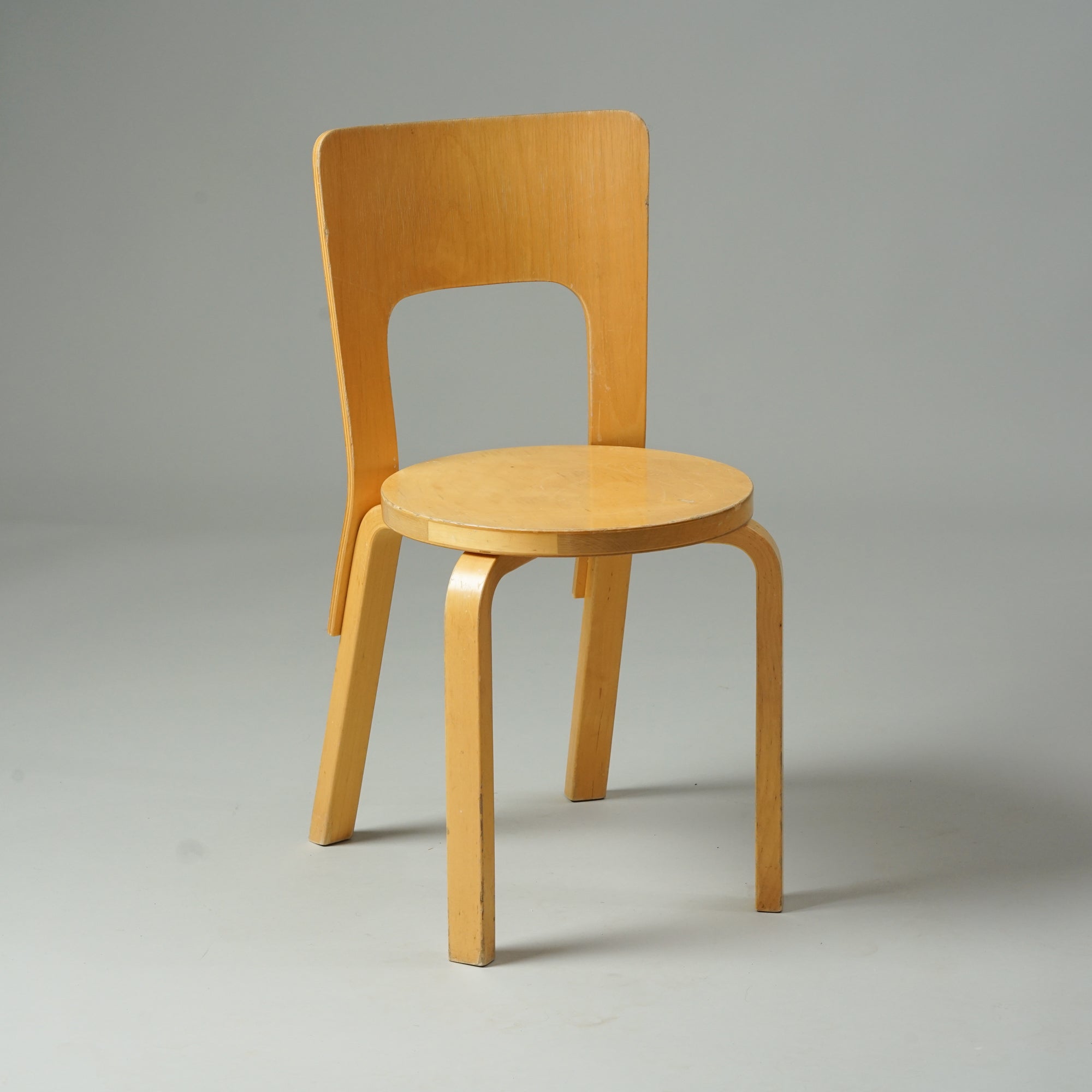 Koivusta tehty tuoli, jossa neljä jalkaa, selkänoja ja pyöreä istuin.