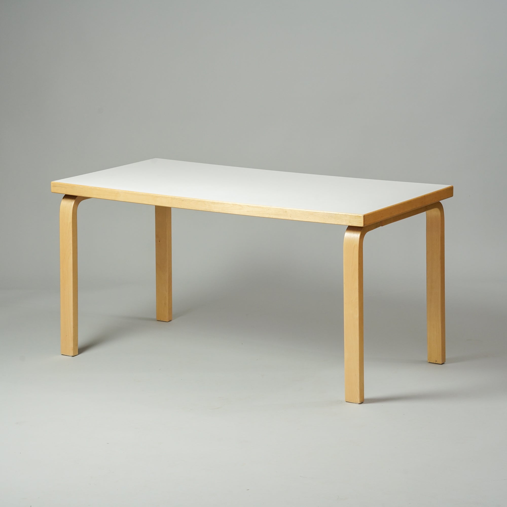 Matala pöytä, joka on tehty koivusta ja jossa on valkoinen linoleumi päällinen.