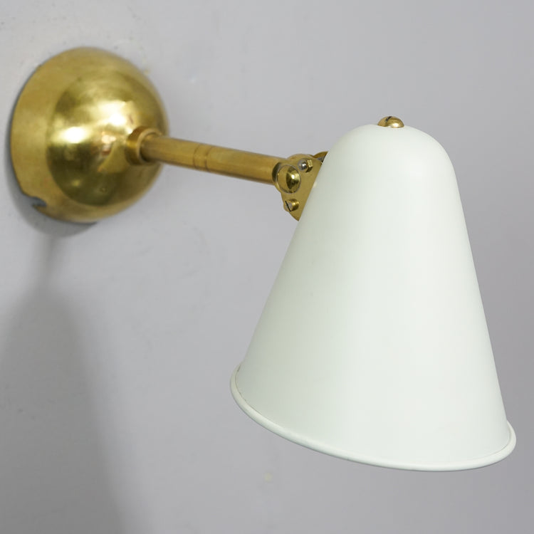 Brass frame wall lamp with metal shade that has been painted white.