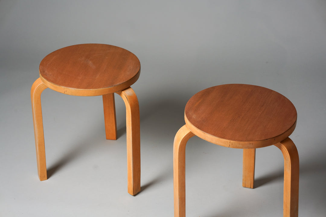 A three legged stool with a birch frame and teak seat. The seat part is round.