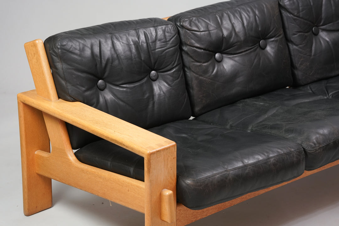 3 seater sofa with oak frame and black leather seating.